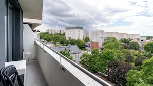 Un balcón con vista a un paisaje urbano, que incluye edificios y árboles.