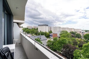 Un balcon donnant sur un paysage urbain, avec des bâtiments et des arbres.