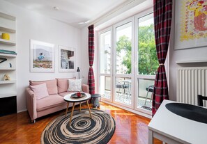Ein modernes Wohnzimmer mit einer Couch, einem kleinen runden Tisch und einem großen Fenster mit Vorhängen.
