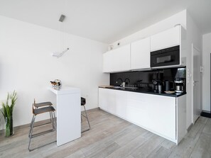 Eine moderne Küche mit weißen Schränken, einer schwarzen Arbeitsplatte, einem eingebauten Backofen und einer Kaffeemaschine.