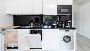 Uma cozinha compacta com lava-louças embutida, cafeteira e máquina de lavar roupa.