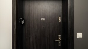 Uma porta de madeira escura com teclado numérico, fechadura e puxador.