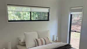 A bedroom with a bed, a nightstand, a window, and a ceiling fan.