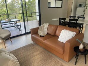 Een moderne woonkamer met een leren bank, een eettafel en stoelen.