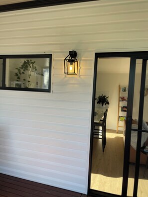 A room with a sliding door, a wall-mounted light fixture, a mirror, and a wooden floor.