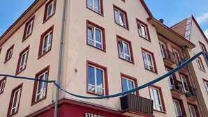 Un edificio a più piani con facciata beige, infissi rossi e un balcone visibile sul lato destro.