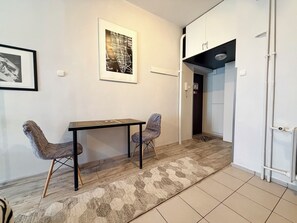 A room with a wooden table, two chairs, a patterned rug, a framed map on the wall, and a white cabinet. - Wrocław Rynek Downtown Studio (Wrocław)
