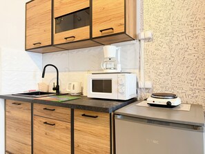 A kitchen with wooden cabinets, a microwave, a coffee maker, and a dishwasher. - Wrocław Rynek Downtown Studio (Wrocław)