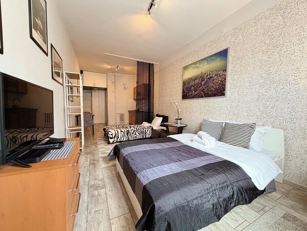 A bedroom with a bed, a desk, a chair, a wardrobe, and a bathroom visible in the background. - Wrocław Rynek Downtown Studio (Wrocław)