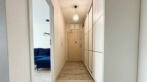A hallway with a wooden floor, a blue sofa, and a wardrobe with sliding doors. - Czartoryskiego Chic Apartment (Wrocław)