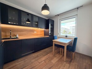 Eine moderne Küche mit dunklen Schränken, einer Holz Arbeitsplatte und einem Essbereich mit Tisch und Stühlen.