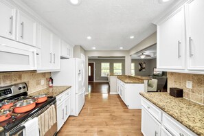 A kitchen with white cabinets, a stove, and granite countertops. - Spacious 4-bedroom house in perfect Houston with cool AC (Houston)