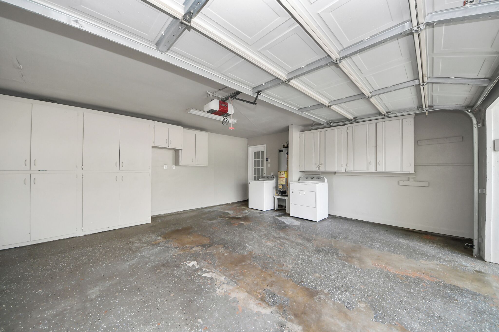 A garage with white cabinets, a washing machine, and a ceiling-mounted projector.