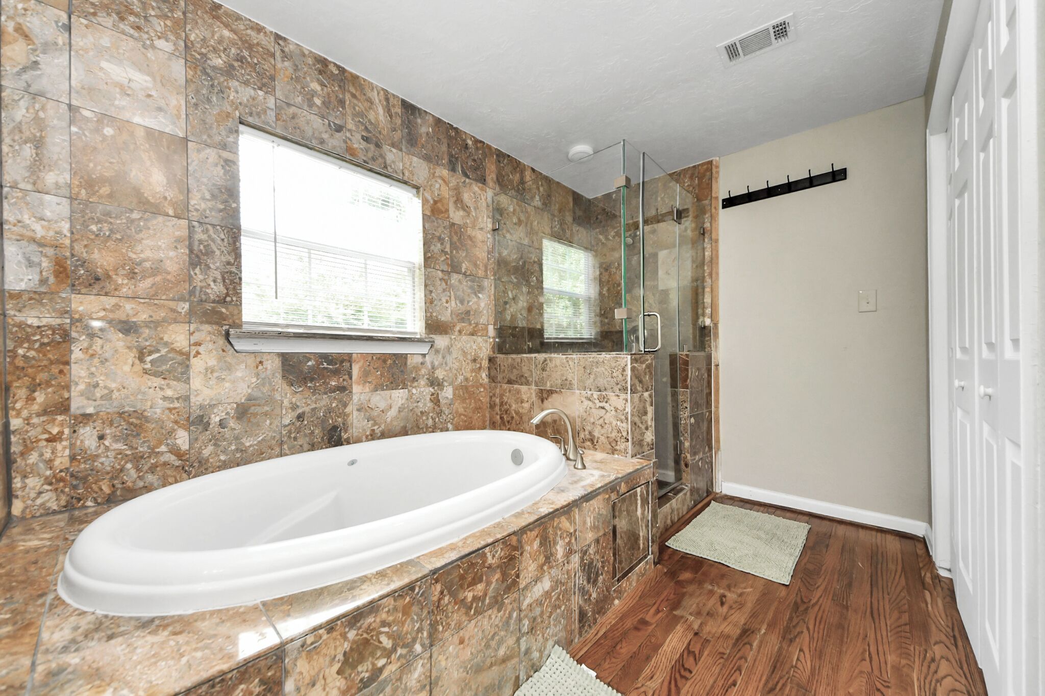 A bathroom with a large bathtub, a glass shower enclosure, and a window.