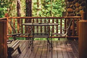 A wooden deck with a table and chairs, surrounded by a stone wall and forest. - Trail Ridge Retreat - Secluded Hocking Hills Cabin (Laurelville)