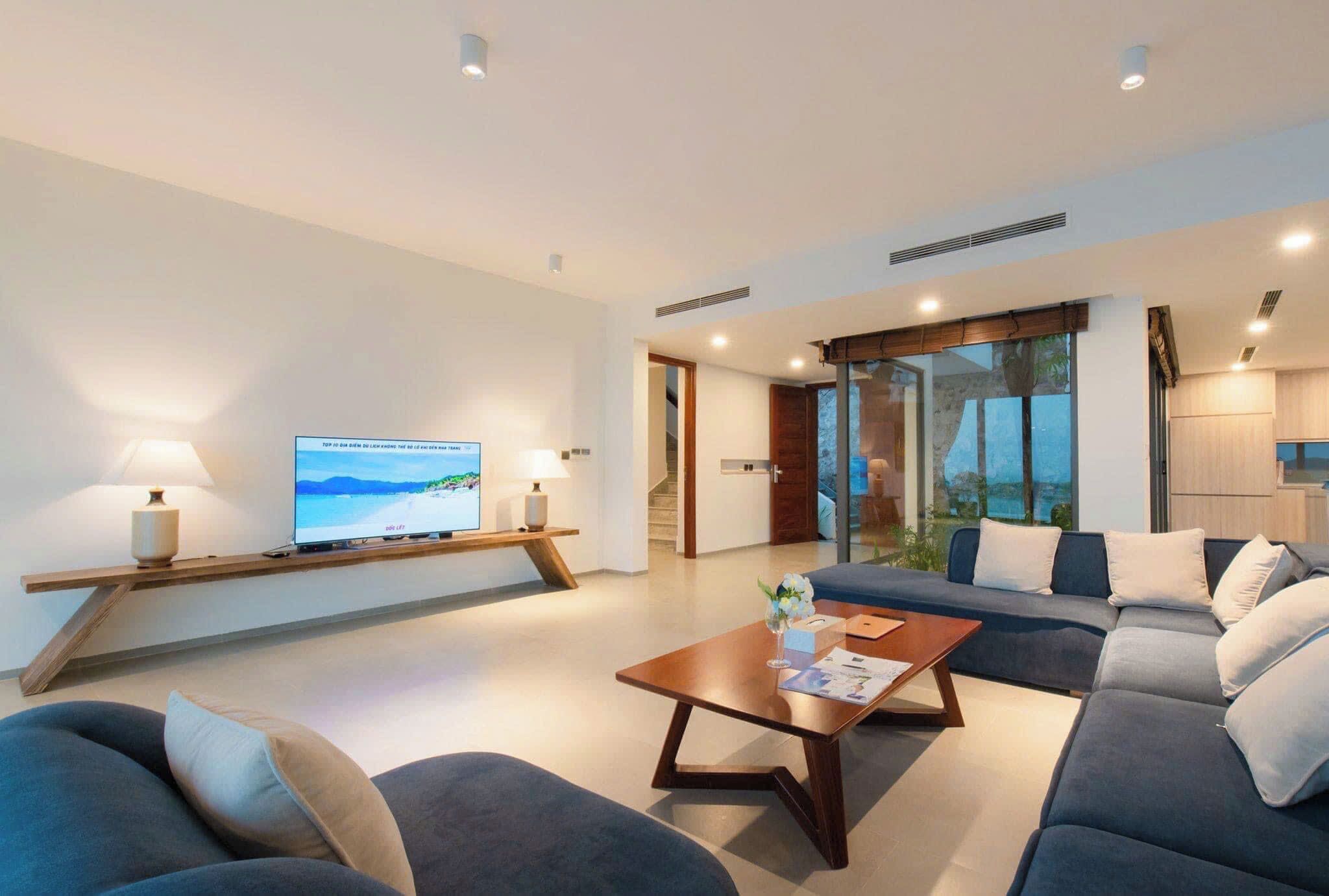 A modern living room with a flat-screen TV, a sofa, a coffee table, and a view of the outdoors.
