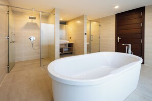 Une salle de bain moderne avec une baignoire sur pieds, une douche à parois de verre et une porte en bois.