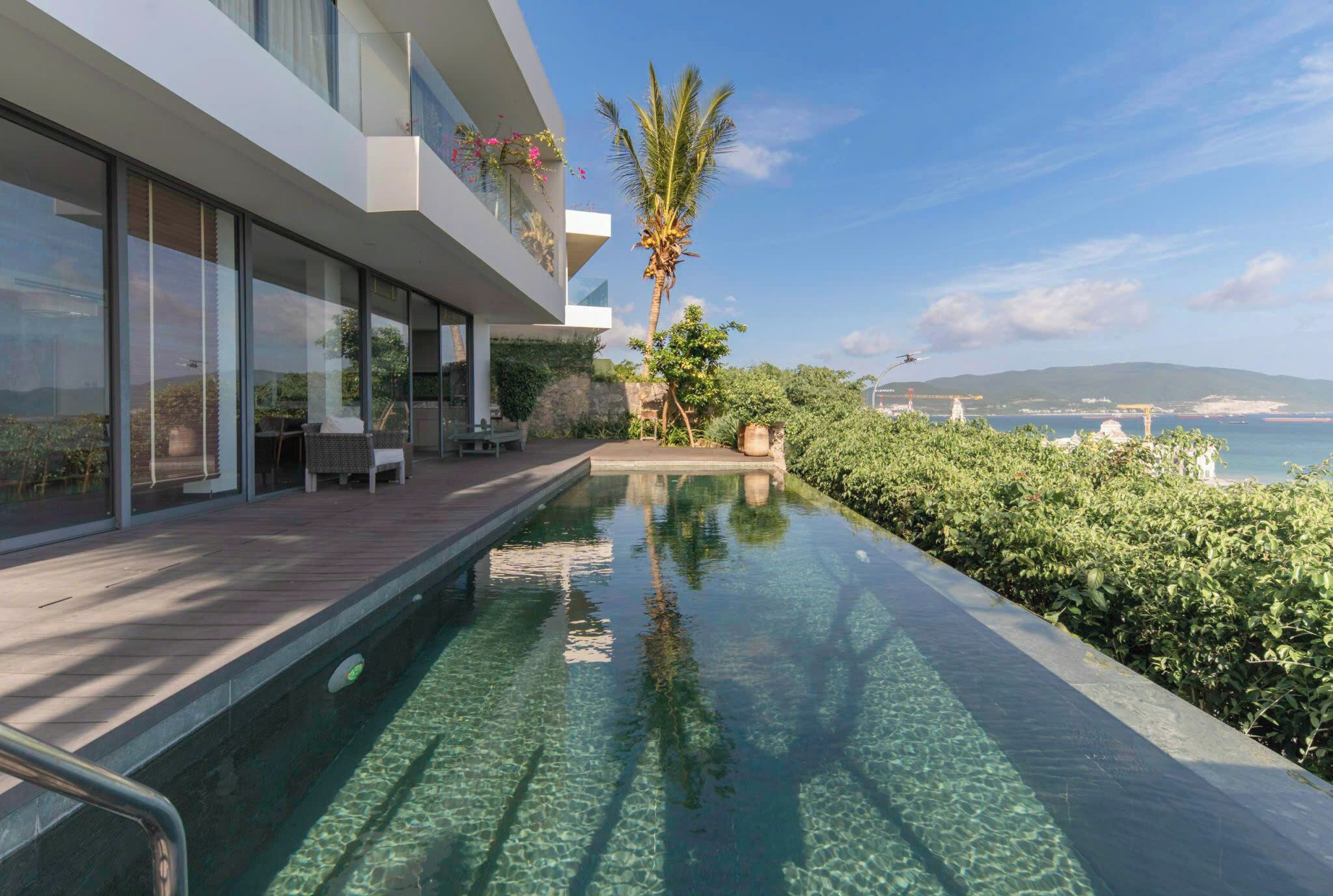 A modern building with a pool, outdoor seating, and a view of the sea.