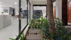 A modern interior with a glass wall, a stone pathway, and indoor plants. - Anh Nguyen Oceanfront Villas (Nam Nha Trang)