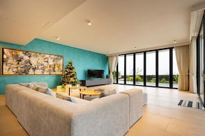 A modern living room with a large sofa, a coffee table, a television, and a Christmas tree. - Anh Nguyen Oceanfront Villas (Nha Trang)