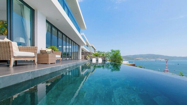 Un hotel moderno con piscina infinita, asientos al aire libre y vista al mar.