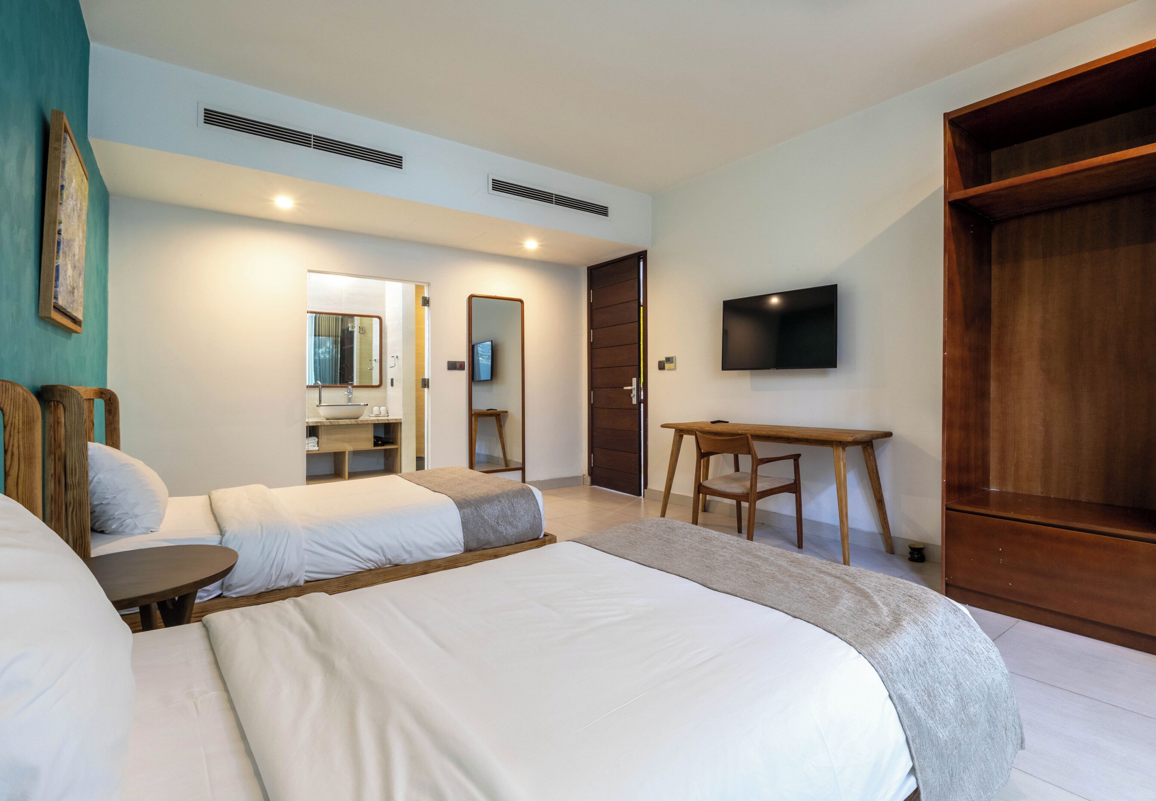 Une chambre d’hôtel avec deux lits, un bureau, une télévision et une armoire.