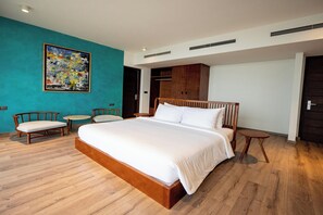 Ein modernes Schlafzimmer mit einem großen Bett, einem Holz-Kopfteil, einem kleinen runden Tisch, zwei Stühlen und einem großen abstrakten Gemälde an der Wand.
