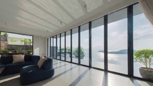 A spacious room with a large window, a sofa, and a potted plant.