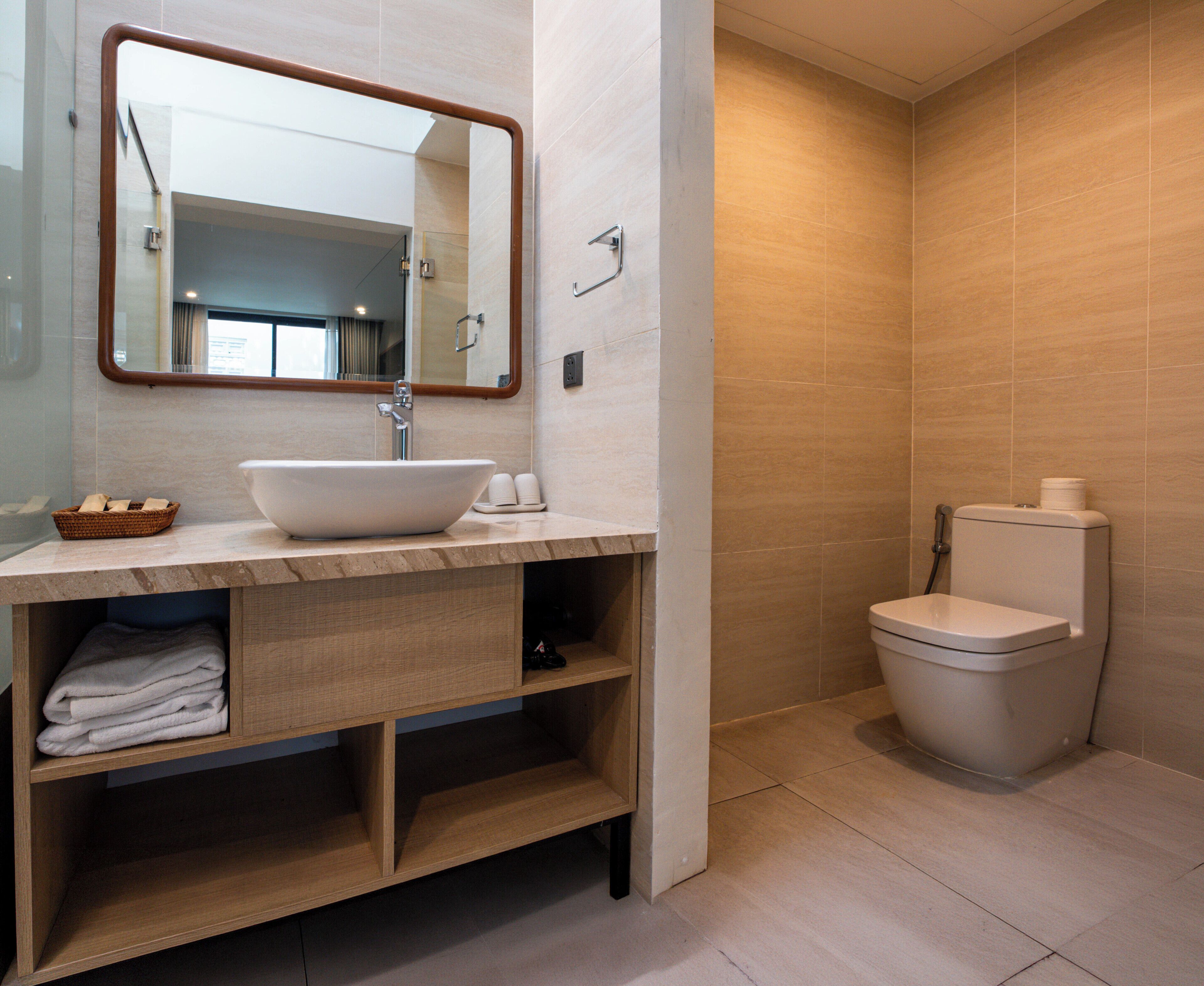 Un baño moderno con lavamanos, espejo e inodoro.