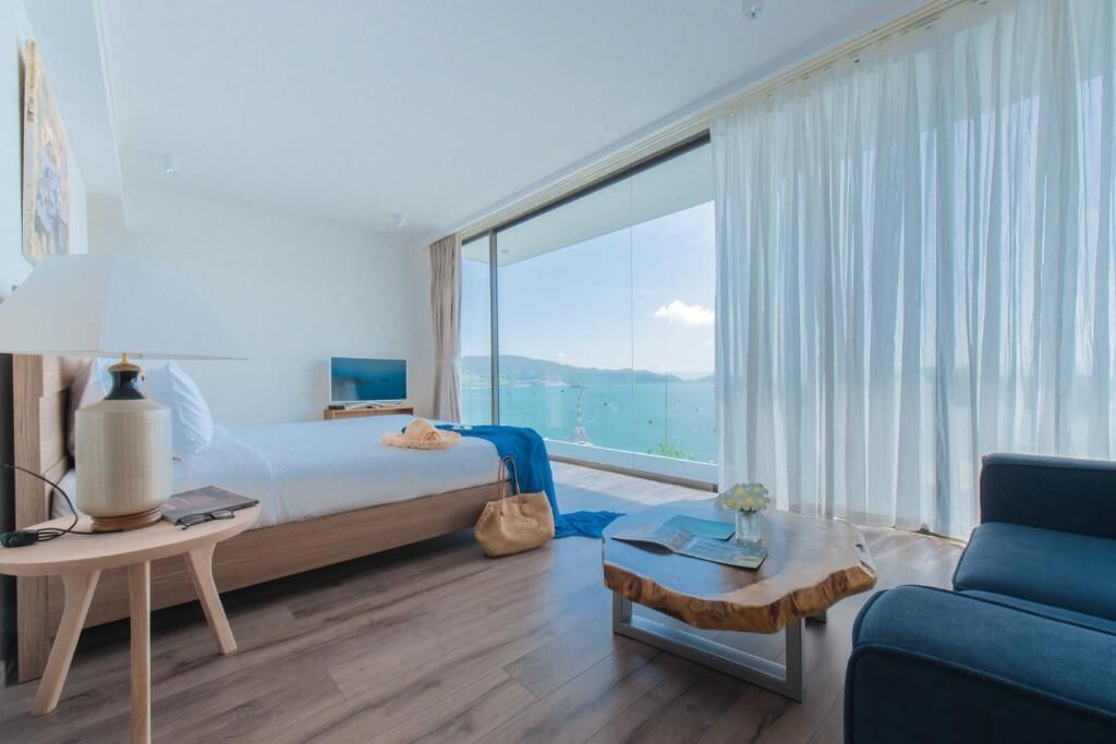 Ein Hotelzimmer mit einem Bett, einem Schreibtisch, einem Sessel, einem Fernseher und einem großen Fenster mit Blick.