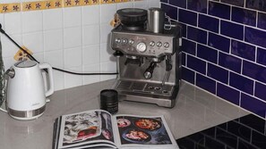 Een koffieapparaat, een waterkoker en een tijdschrift op een aanrecht.