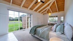 Ein Schlafzimmer mit großem Fenster, einem Bett und einer Holzzieldecke.