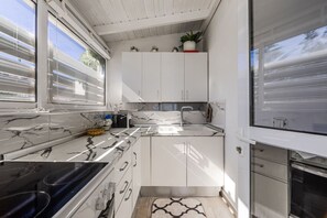 A modern kitchen with white cabinets, a marble countertop, and a built-in oven. - Blue Bay Sea View Apartment With Free Parking (Himarë)