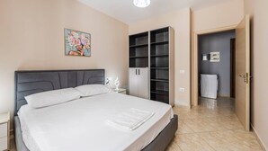Un dormitorio con cama, mesita de noche, armario y puerta que da a un baño.