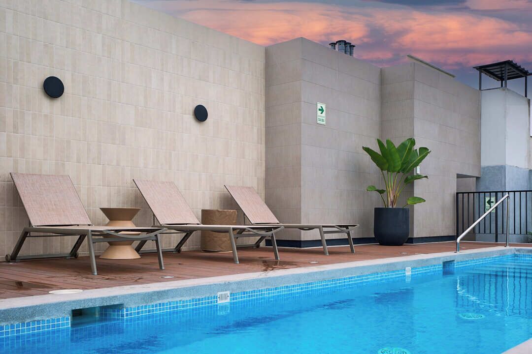 Un espace piscine avec des chaises longues, une plante en pot et un panneau indiquant une direction.