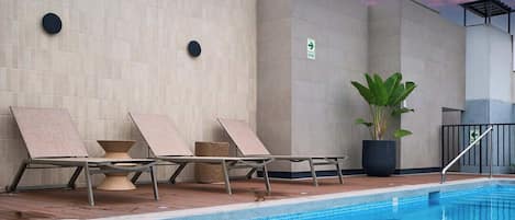 A pool area with lounge chairs, a potted plant, and a sign indicating a direction.