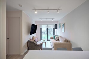 A modern living room with a sofa, armchairs, a flat-screen TV, and a dining area. - Miraflores via Larcomar / gym / Balcón Street and pool (Miraflores)