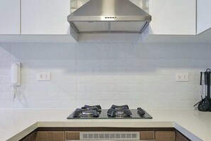 A kitchen with a gas stove, a range hood, and a phone on the wall. - Miraflores via Larcomar / gym / Balcón Street and pool (Miraflores)