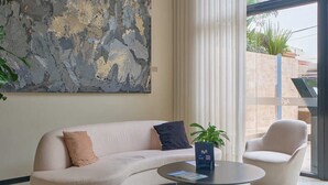 Een moderne woonkamer met een gebogen bank, een ronde salontafel en een groot abstract schilderij aan de muur.