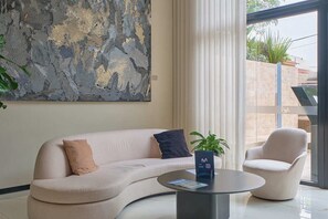 A modern living room with a curved sofa, a round coffee table, and a large abstract painting on the wall. - Miraflores via Larcomar / gym / Balcón Street and pool (Miraflores)