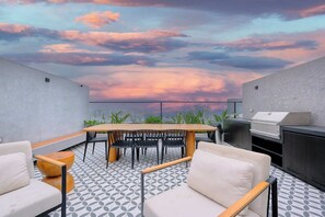 A rooftop terrace with a dining table, chairs, and a grill. - Miraflores via Larcomar / gym / Balcón Street and pool (Miraflores)