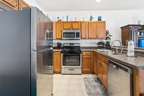 Eine Küche mit Holzausstattung, Edelstahlgeräten, einer Arbeitsplatte aus Granit und einem integrierten Geschirrspüler.
