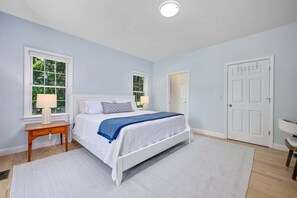 Ein Schlafzimmer mit einem Bett, zwei Nachttischen, einem Fenster und einer Tür.