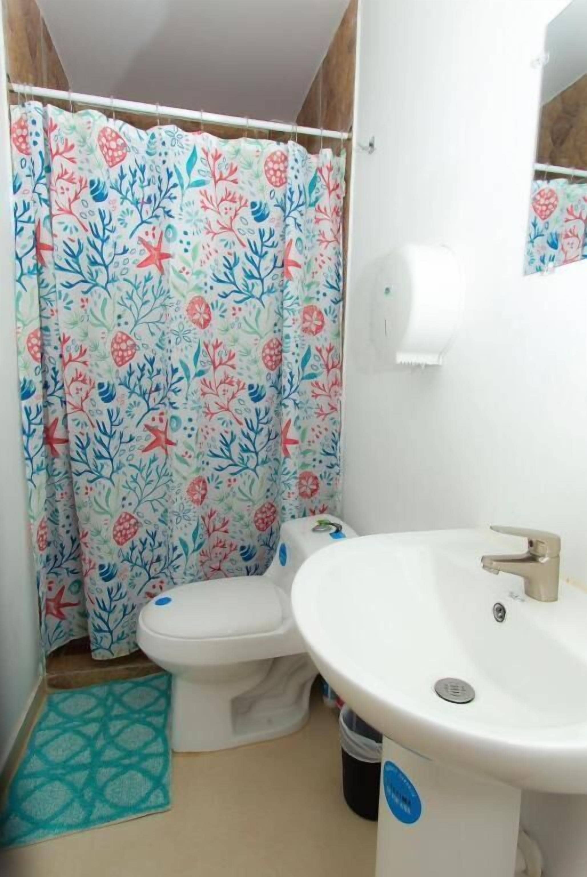 A bathroom with a toilet, sink, and shower curtain.