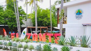 Un hotel llamado 'EL ZONTE' con un letrero, rodeado de plantas tropicales y palmeras.