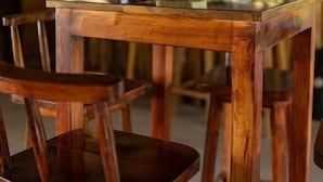 Una barra de madera con sillas, una lámpara colgante y un fondo desenfocado con botellas.