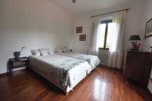 Una camera da letto con un letto matrimoniale, un comodino con una lampada, una cassettiera e una finestra con tende.
