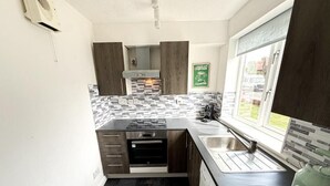 A compact kitchen with a built-in oven, a sink, and a window providing natural light. - 1 Bed - Sleeps 4 - WiFi & Free Parking (Redhill)