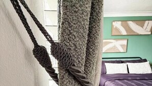 A room with a bed, a curtain with a rope, and a wall with a painting. - 1 Bed - Sleeps 4 - WiFi & Free Parking (Redhill)