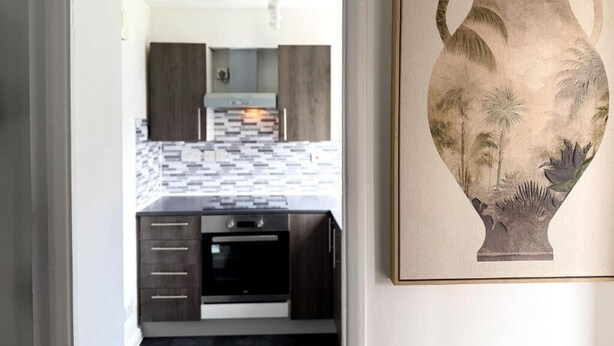 A modern kitchen with dark cabinetry, a tiled backsplash, and a central island. - 1 Bed - Sleeps 4 - WiFi & Free Parking (Redhill)
